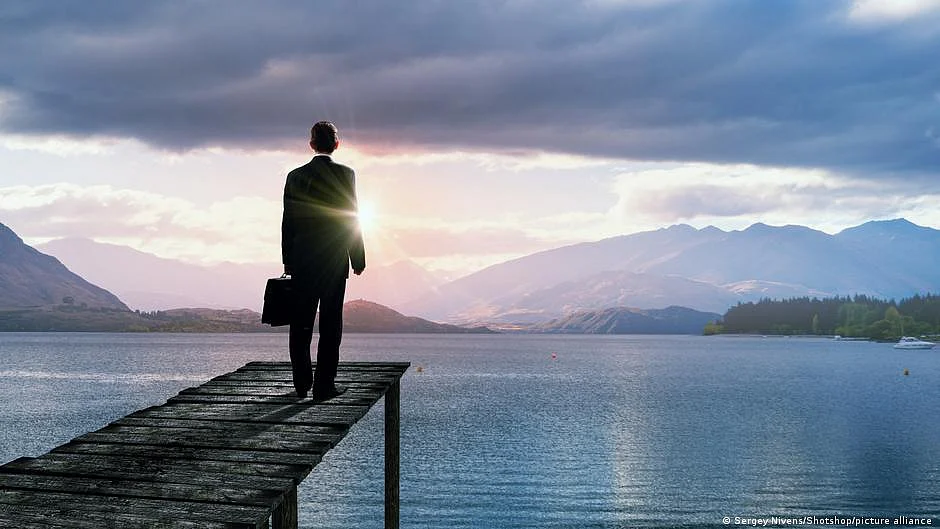 A man wearing a suit, standing at the edge of a river (photo: DW)
