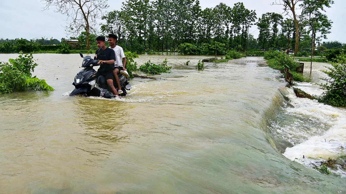 A man rides his two-wheeler as he wades through a flooded road following a heavy rain in Kampur, Nagaon District of Assam on Saturday, June 17. (photo: IANS)
