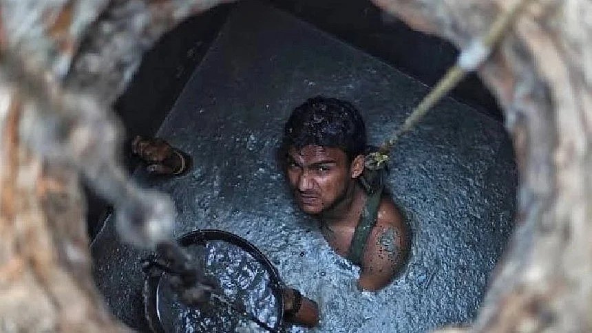 A sanitation worker cleans a sewer while standing neck deep in the muck