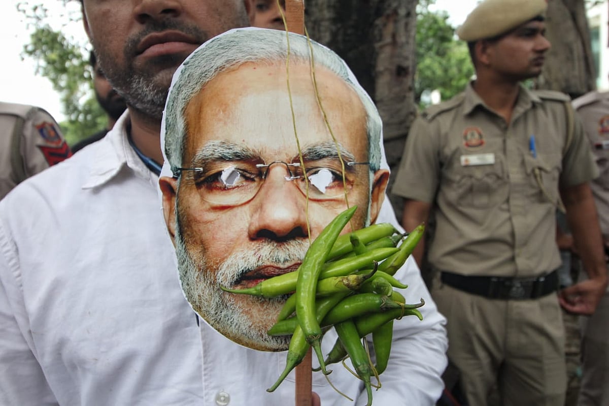 A protester holds a cutout of Modi's face  with chillies on it (photo: Vipin/National Herald)