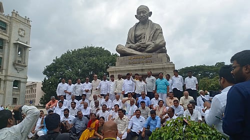 Protesting Karnataka BJP members in front of Mahatma Gandhi's sculpture (Photo: IANS)