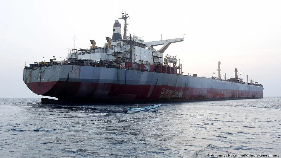 Rusting supertanker with nearby motorboat (photo: DW)