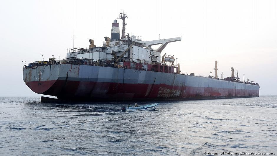Rusting supertanker with nearby motorboat (photo: DW)