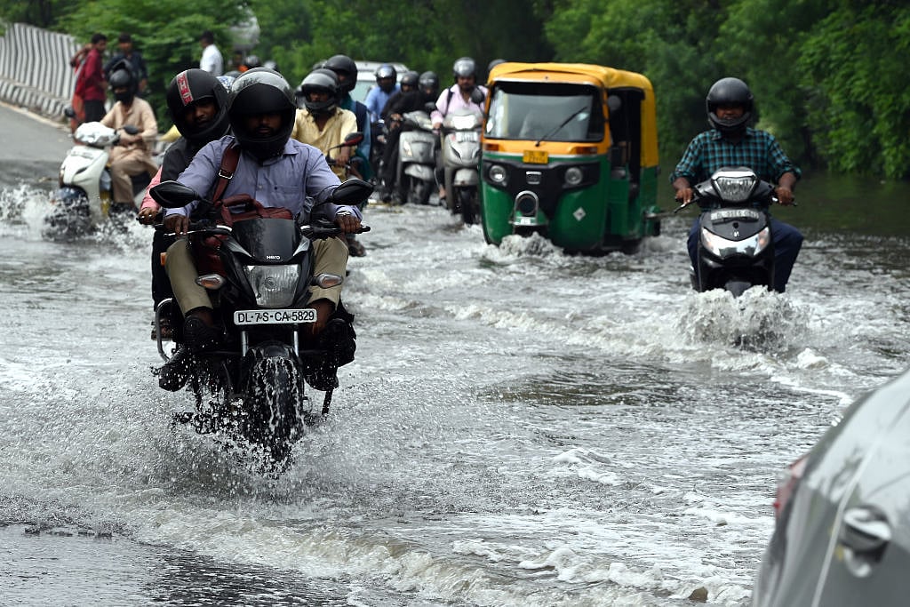 Motorcyclist drives through a flooded street in New Delhi (Photo: Getty Images)