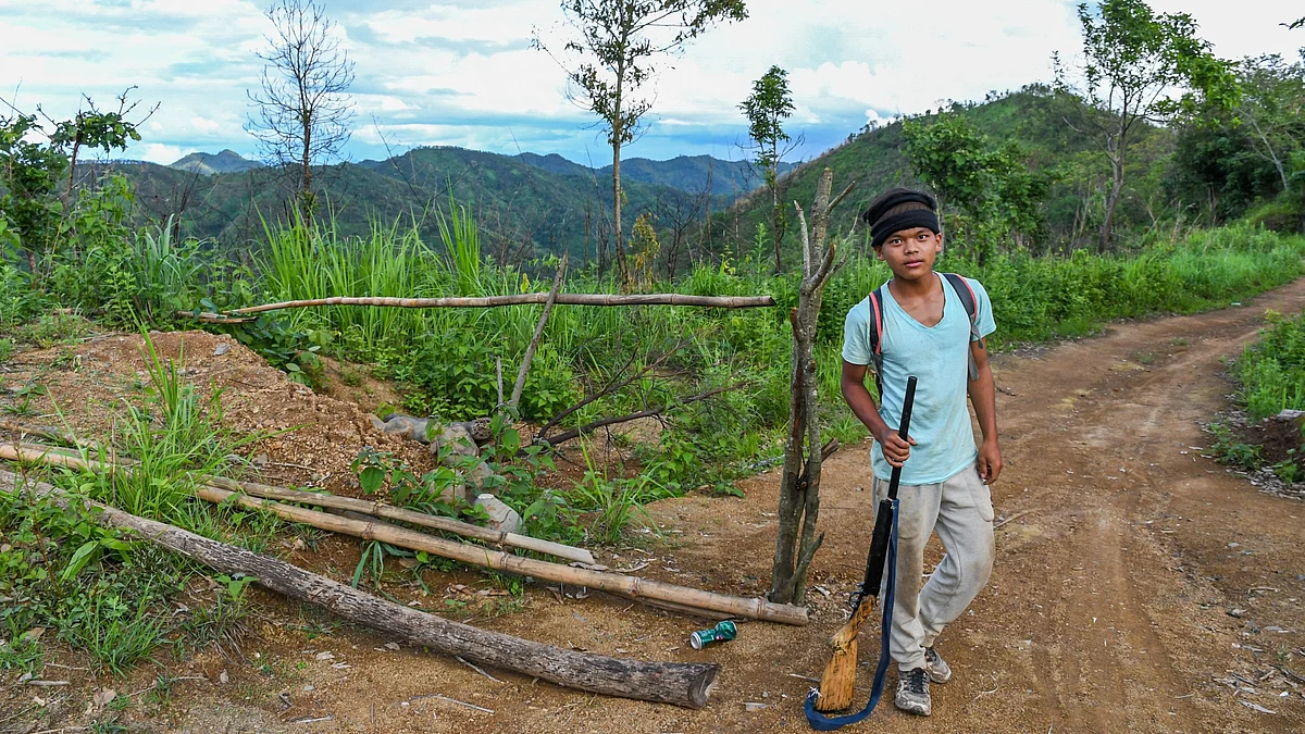 Henry, 14, belongs to a Kuki tribe. Here he poses with his gun after completing his frontline duty at Dampi village in Churachandpur district, Manipur on 22 June 2023 (photo by Biplov Bhuyan/SOPA Images/LightRocket via Getty Images)