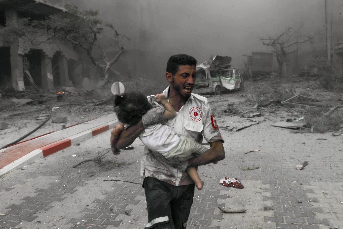 A medical worker rushes a child to an ambulance for treatment after Israeli airstrikes in Gaza City (photo: Getty Images)