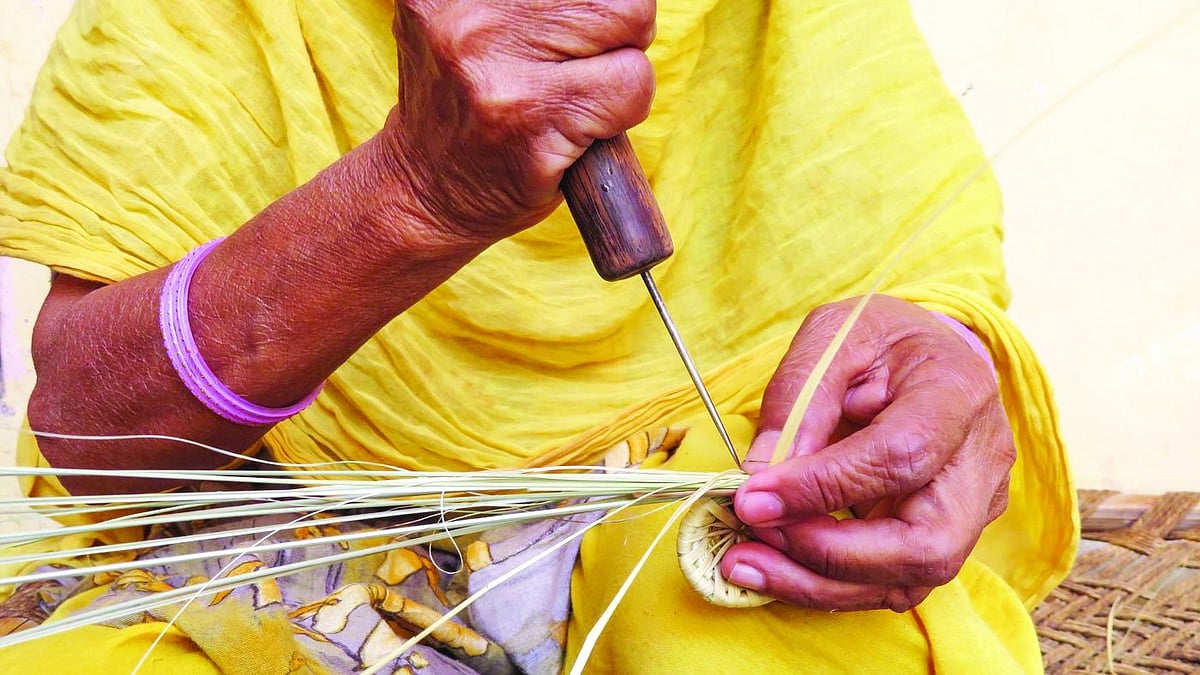 A woman weaves with sirahi, a sharp needle.