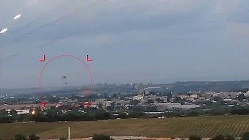 Rockets are seen shooting over a settlement in the Gaza strip while a paratrooper lands during the Hamas attack on Israel on 7 October 2023 (photo: IANS)