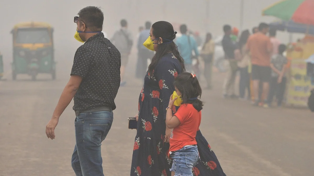 Representative photo of a family in Delhi, both adults and a young child wearing pollution masks, walking through a busy street thick with smog (photo: National Herald archives)