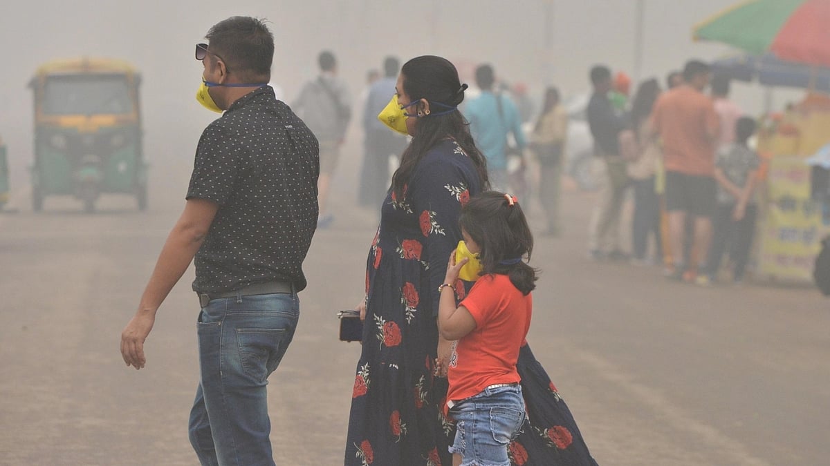 Representative photo of a family in Delhi, both adults and a young child wearing pollution masks, walking through a busy street thick with smog (photo: National Herald archives)
