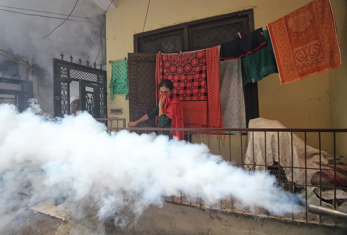 A woman standing on her covers her nose and mouth as the fumes rise from the streets (photo: Vipin/National Herald)