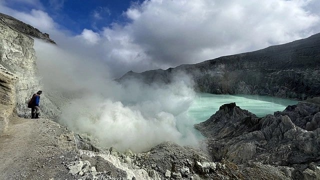 The author approaches an acidic  crater lake in Mt Ijen, East Java, through a wreath of roiling smoke. It is also known for its blue fire (photo courtesy Timira)