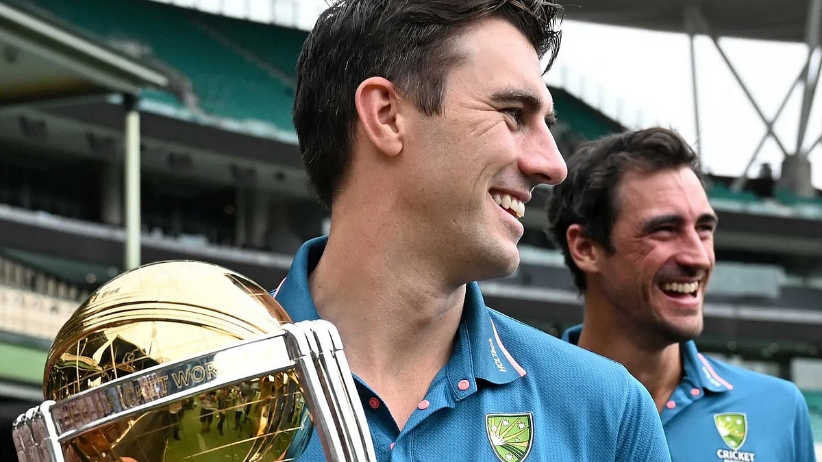 Australian cricket team captain Pat Cummins holds the 2023 ICC World Cup trophy, with teammate Mitchell Starc behind him, as they share a laugh in Sydney on 28 November (photo: ICC)