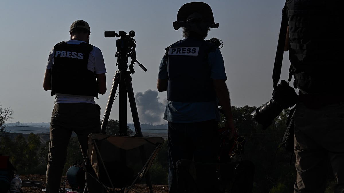 Members of the media photograph and film to an incoming IDF strike on buildings in Gaza City, as seen from the border area in October  (Photo: Alexi J. Rosenfeld/Getty Images)