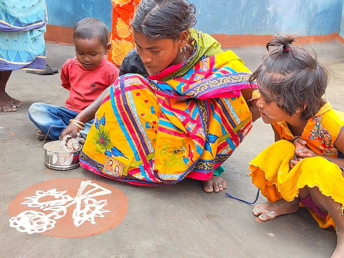 Householders decorate their homes ahead of Bandna, here with alpona drawn with a paste of ground-up rice on a frame of red earth (geru mati) in the courtyards; children watch and learn (photo: PARI) 