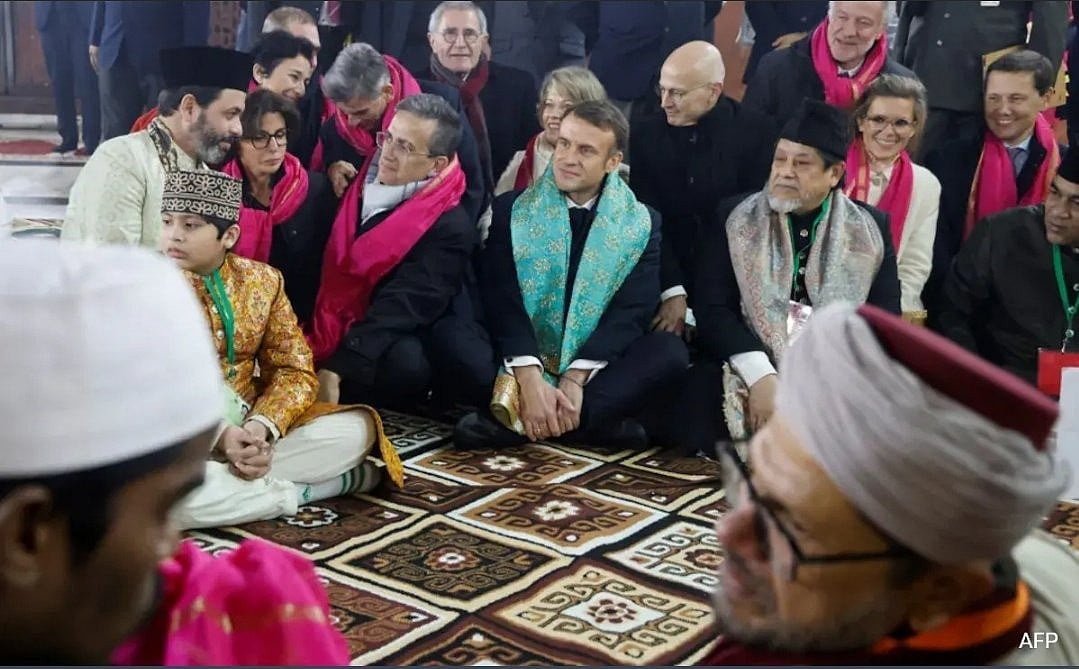 President Emmanuel Macron of France (at centre, with green shawl) with guests at the iconic 700-year-old shrine of the Nizamuddin Dargah — considered a key centre of Sufi culture in India (photo courtesy @joBeeGeorgeous/X)