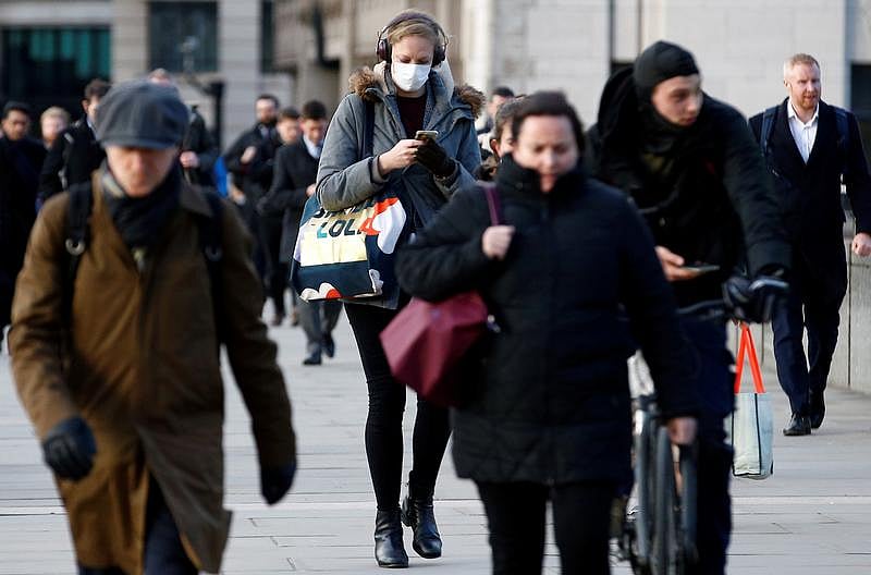 Young Londoners walk the pavements dressed for  winter. One of them is wearing a mask.
