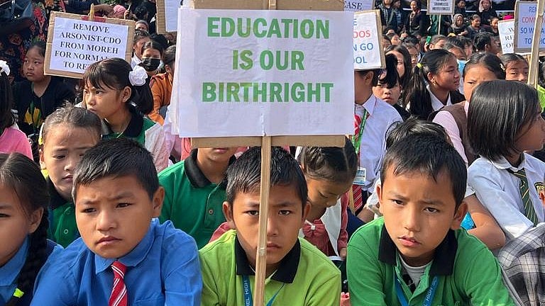 Students' sit-in in Moreh, Manipur, on the border of Myanmar on 27 January 2024, demanding reopening of schools. The child in centre front holds a placard saying 'Education is out birthright' (photo courtesy @KSO_Lamka/X)