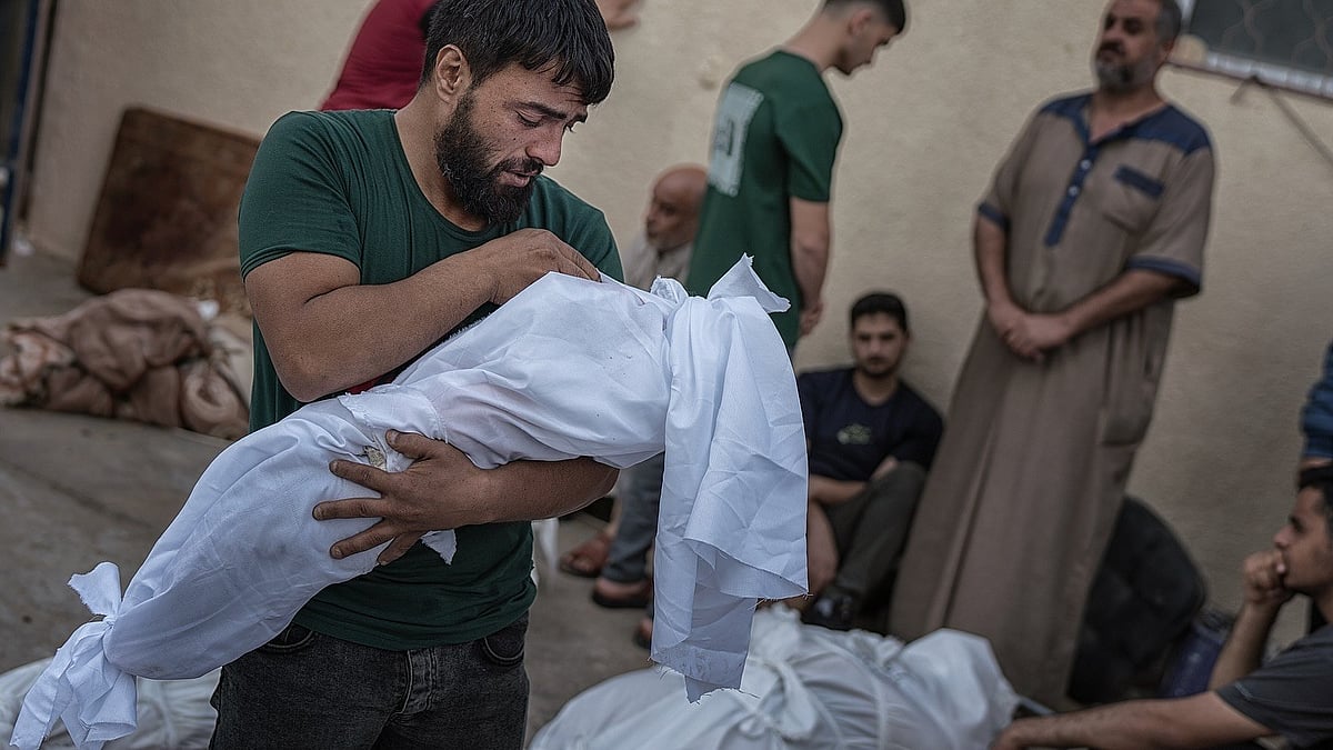 A man holds the shroud-wrapped body of a child. Over 14,000 of Gaza’s 1.1 million children have been killed by Israeli forces since 7 October 2023 (photo courtesy @motaz_azaiza/Instagram)
