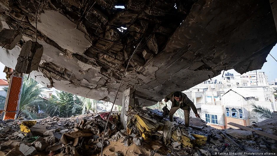 A man looks through precariously held up rubble for survivors in Rafah (photo: DW)