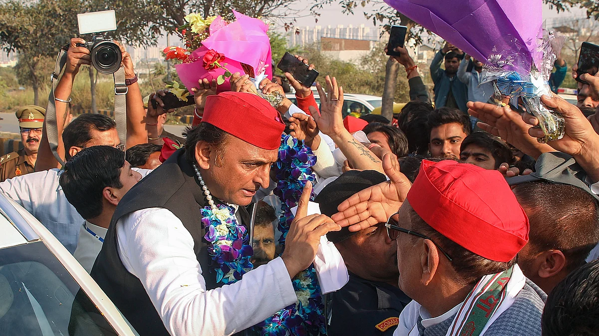 Samajwadi Party president Akhilesh Yadav (in garland and red cap) being welcomed by supporters in Noida, 6 March 2024 (photo: PTI)
