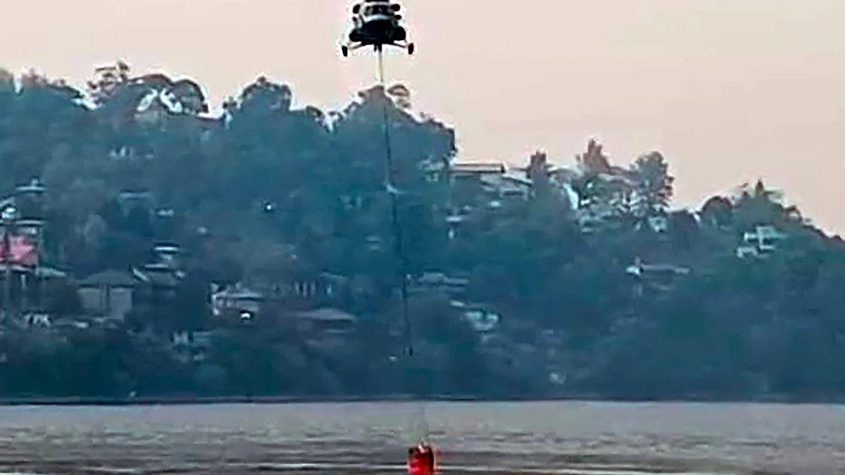 A helicopter fills water from Bhimtal Lake, to be used to control the forest fire in Nainital on 27 April (photo: PTI)