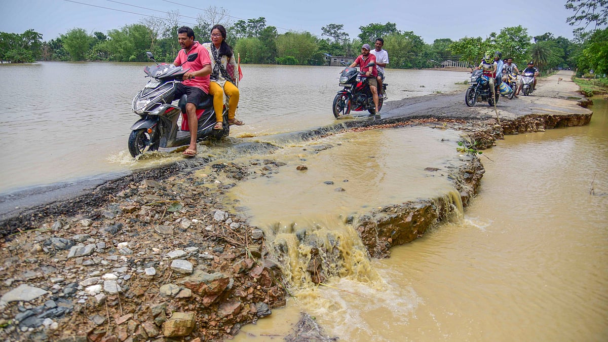 Bikers wade through a flooded area following rains in Nagaon district on 2 June (photo: PTI)