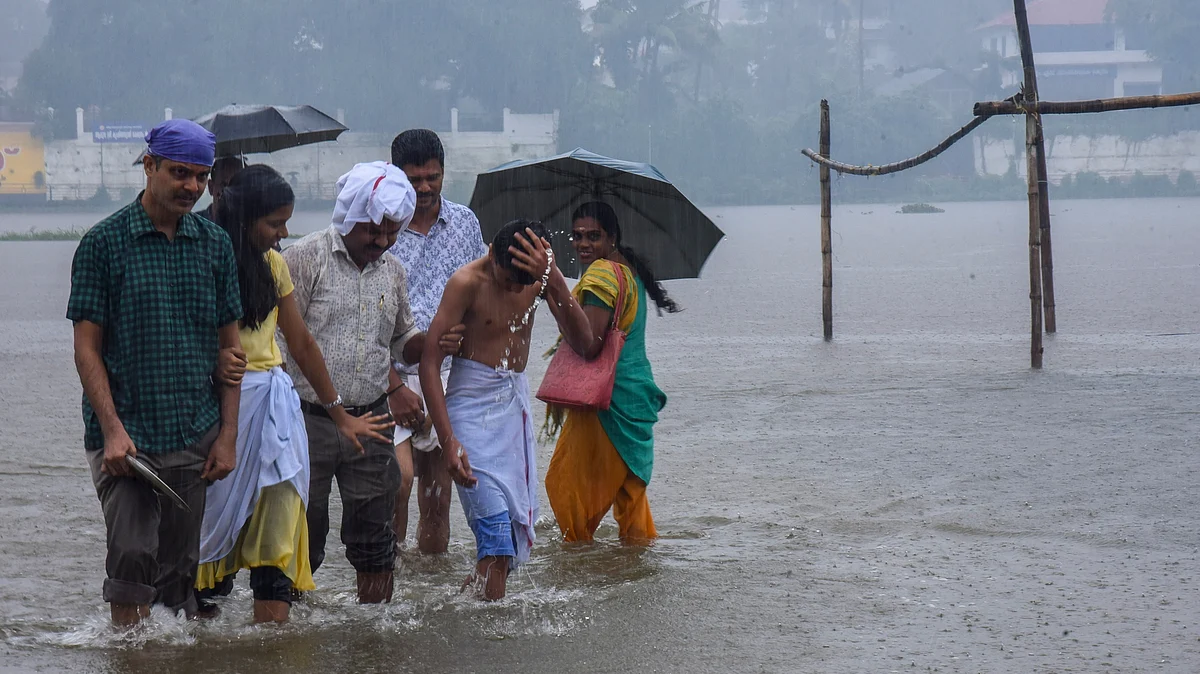 People wade through a waterlogged street in Kochi on 27 June (photo: PTI)