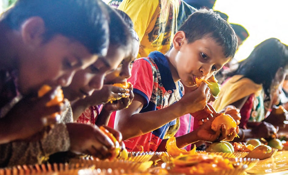 Children enjoy mangoes at a party (photo: Getty Images)