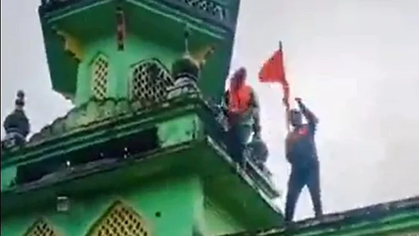 Screengrab that shows men atop the mosque in Gajapur (photo: @WaqarHasan1231/X)