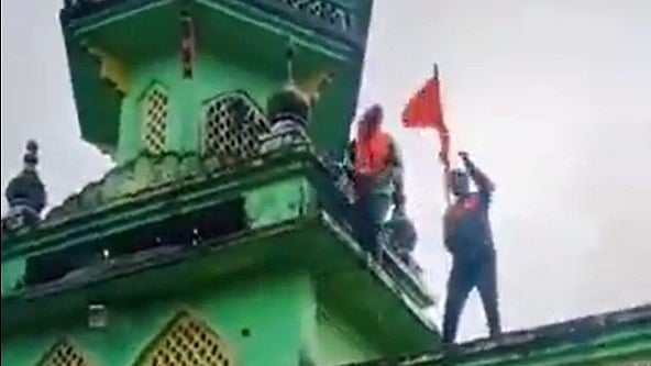 Screengrab that shows men atop the mosque in Gajapur (photo: @WaqarHasan1231/X)