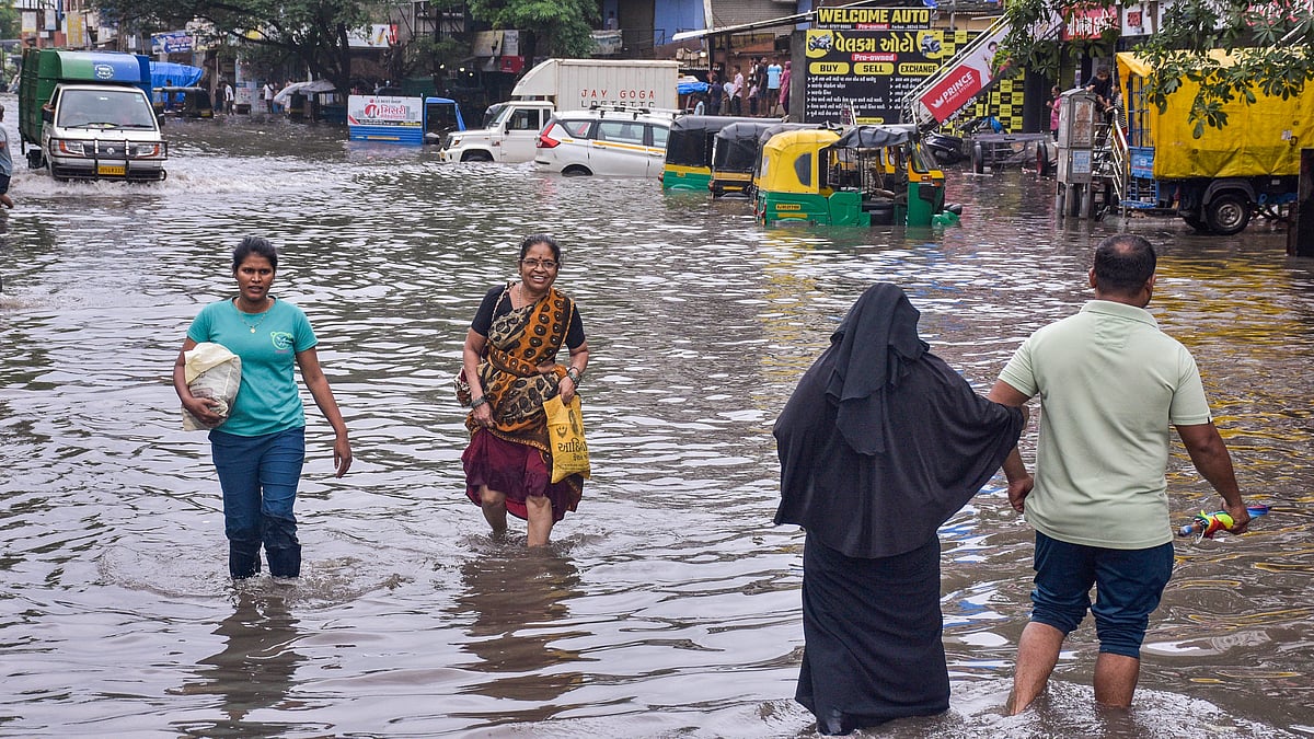 Surat: People wade through a waterlogged road at Ved Darwaja after heavy rainfall