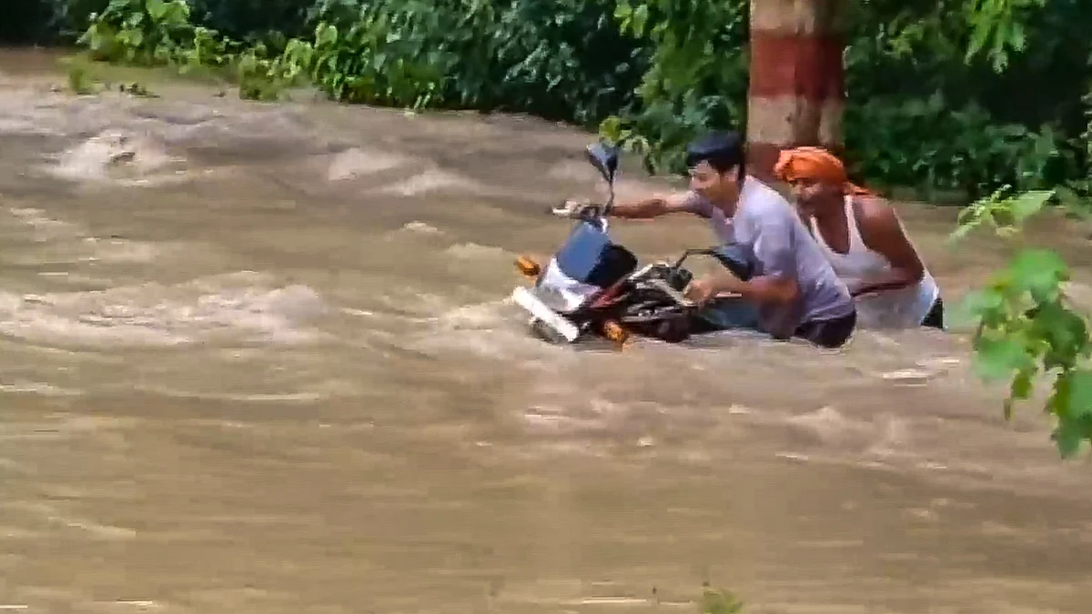 Commuters wade through a flooded area in Bagaha on 28 September (photo: PTI)