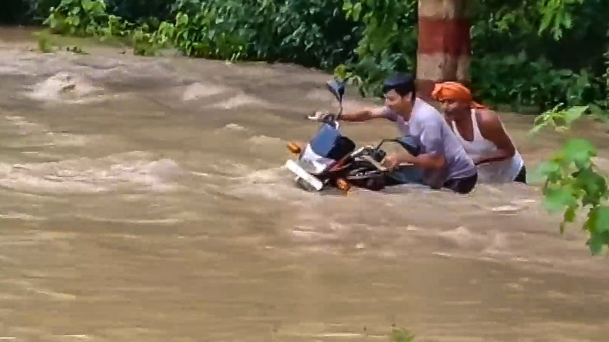 Commuters wade through a flooded area in Bagaha on 28 September (photo: PTI)