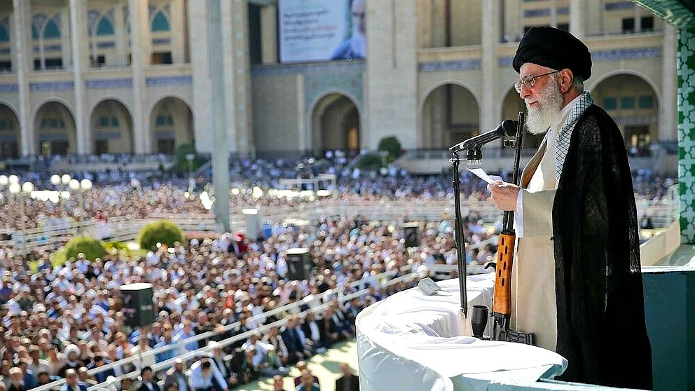Ayatollah Khamenei addresses the gathering with an AK-47 at his side