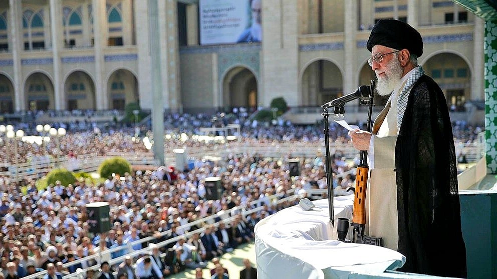 Ayatollah Khamenei addresses the gathering with an AK-47 at his side