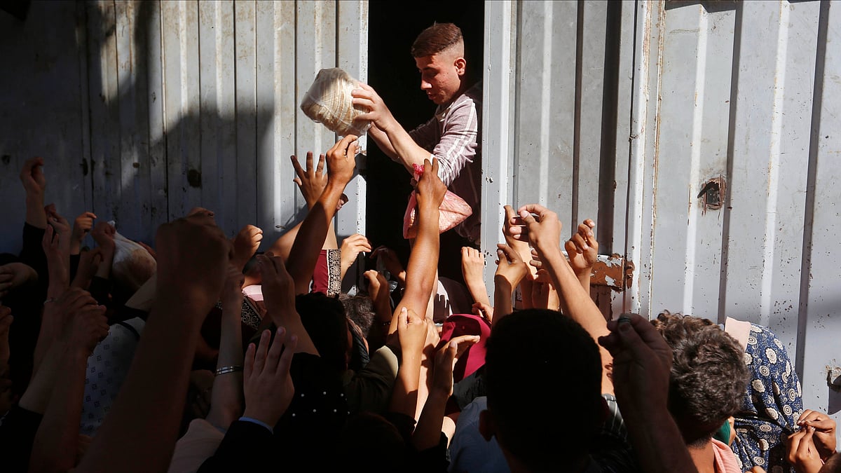 People struggle to get a loaf of bread from an aid truck in Deir al-Balah, Gaza (photo: @UNRWA/X)