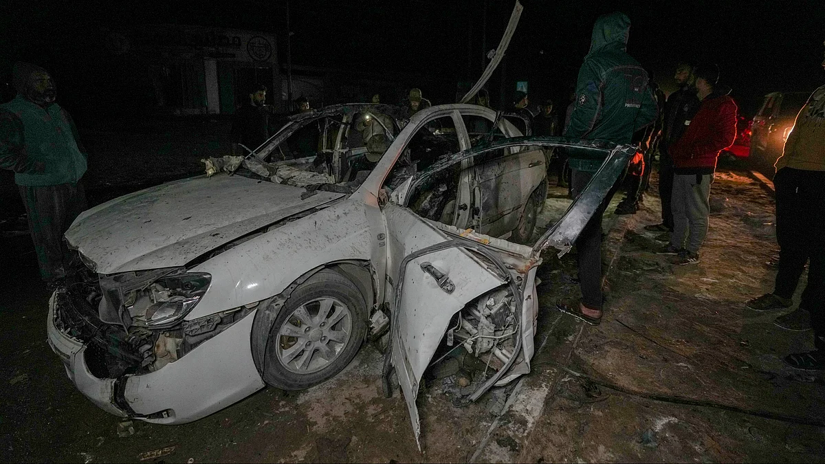 Palestinians inspect a damaged car in central Gaza Strip on 23 December (photo: PTI)