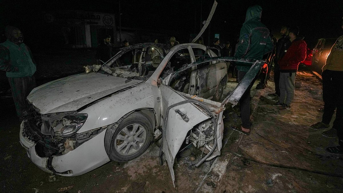 Palestinians inspect a damaged car in central Gaza Strip on 23 December (photo: PTI)