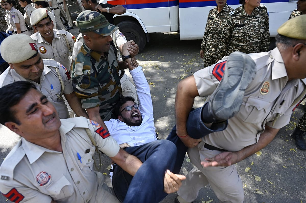 Delhi Police and security forces carrying away a protester