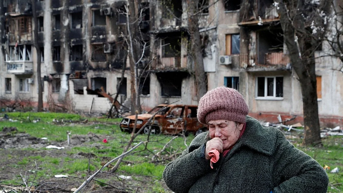 Outside bombed and desolated homes, near a gutted car, an Ukrainian weeps