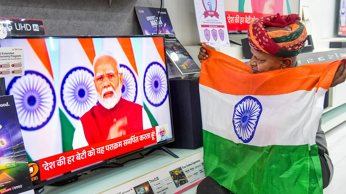 A man listens to the prime minister's speech with a tricolour held to his chest