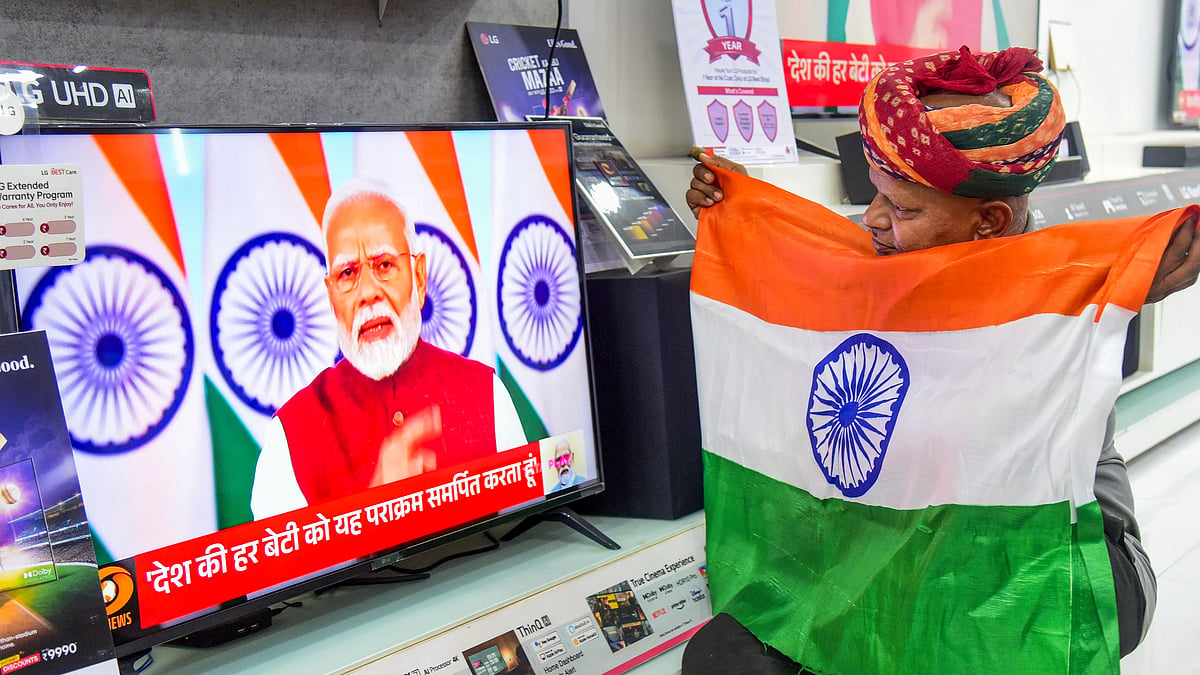 A man listens to the prime minister's speech with a tricolour held to his chest