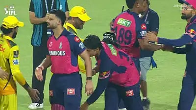 Vaibhav Suryavanshi (centre) reaches for M.S. Dhoni's feet as a mark of respect