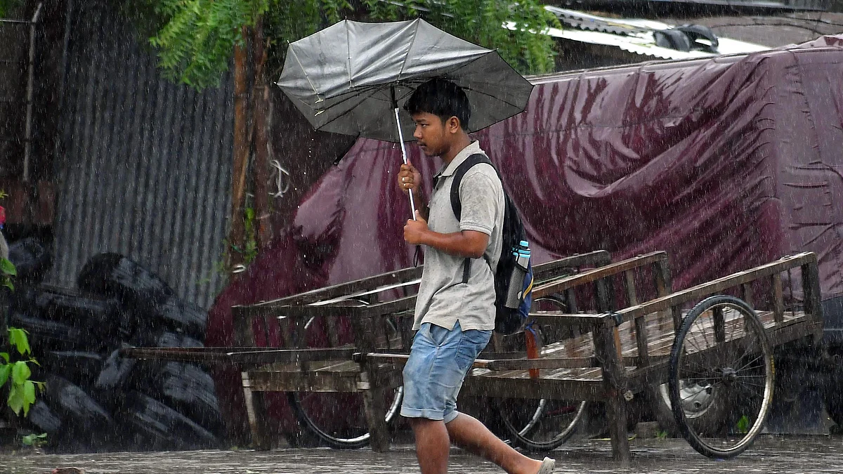A man tries to protect himself from rain (IANS file photo) 