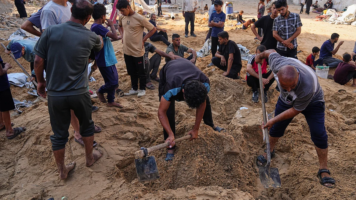 Palestinians dig through sand looking for belongings in Gaza City on 28 June (photo: AP/PTI)