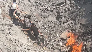 Palestinians try to pull each other out of the crater from a bombing of refugee tents