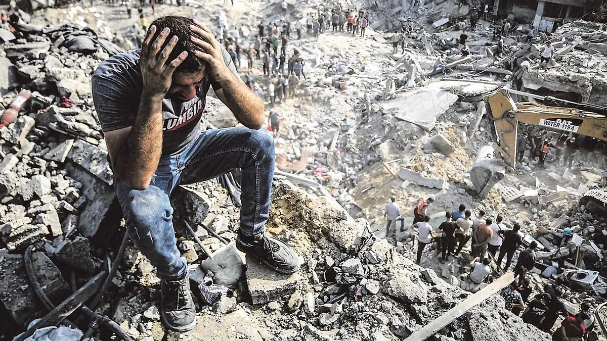A man in Gaza sits atop the rubble in despair, others dig (image courtesy @YusufCatStevens/X)