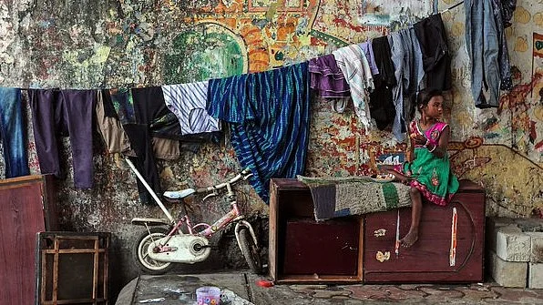 A migrant worker's little girl in Mumbai, with clothesline, cabinet... and her bicycle. Can she travel? 