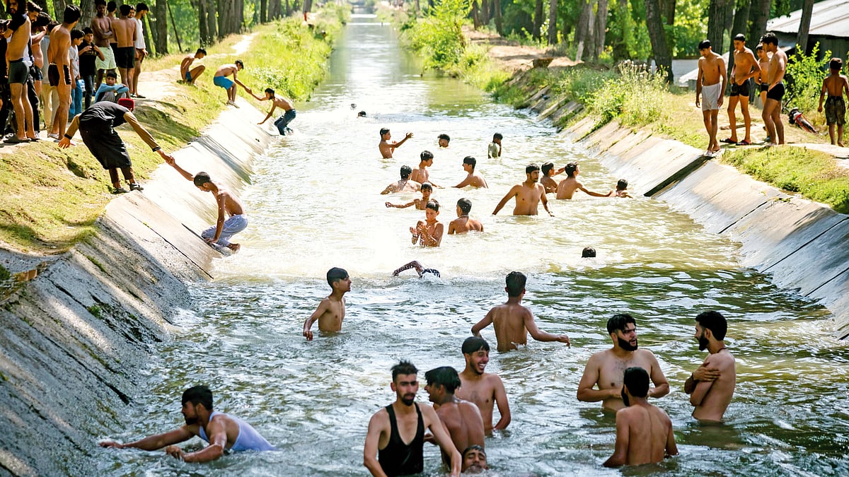 People jump into a canal to beat the heat in Pulwama